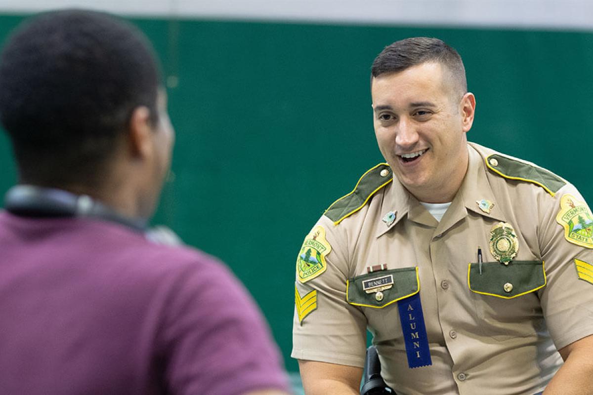 A Westfield State University alumnus in his state police uniform talks to a current student.