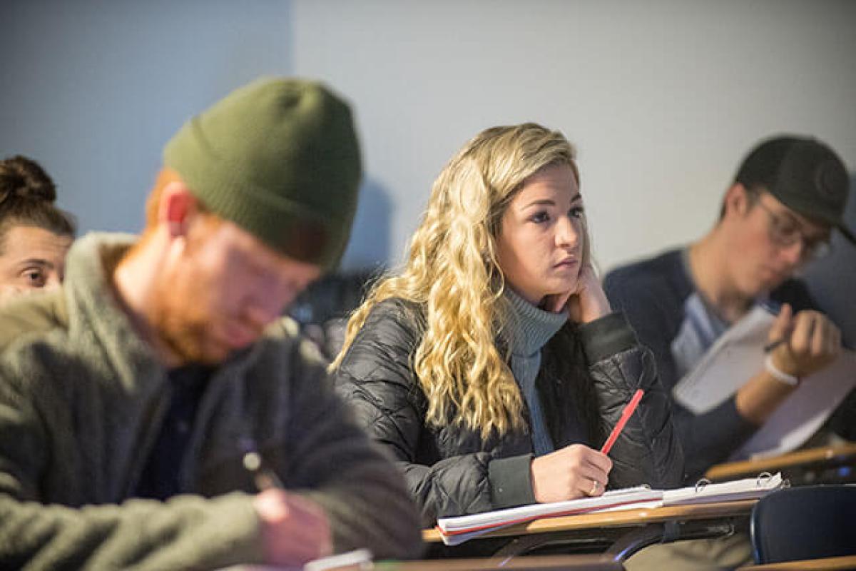 Students take notes while sitting in a classroom.