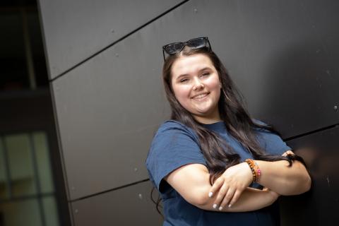 Samantha Grunden, a fair-skinned, brown-eyed young woman with long brown hair and sunglasses on top of her head, smiles against a gray backdrop.