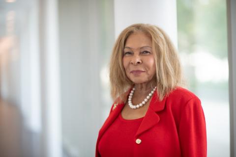 Dr. Linda Thompson in a red suit and standing in front of an open and bright mirror.