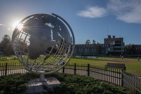 A campus stock photo of the globe. The sun shines behind it.