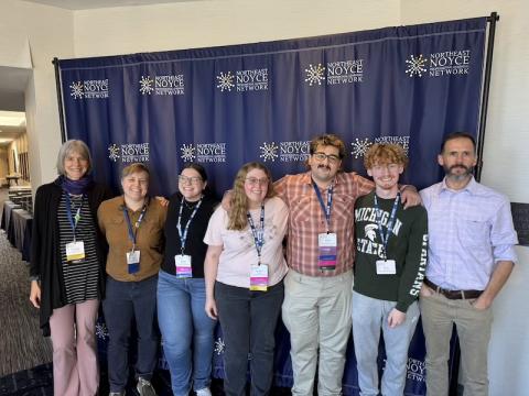 Dr. Christine von Renesse, Dr. Arne Christenson, Aiden Robert ’24, Jessica Peitzsch ’24, Kyle Morandi ’24, and Maddie Boyer ’24 at the 2024 NOYCE conference in Cambridge, MA. They pose together in front of a blue banner.