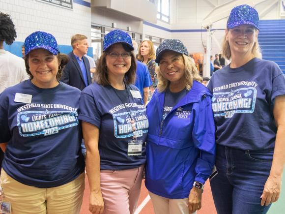 President Linda Thompson and staff wearing Homecoming tee shirts and blue hats.