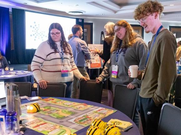 Jessica Peitzsch ’24, Maddie Boyer ’24, Aiden Robert ’24, Kyle Morandi ’24 at the 2024 NOYCE conference. They surround a table where they're interacting with the materials as part of a presentation.