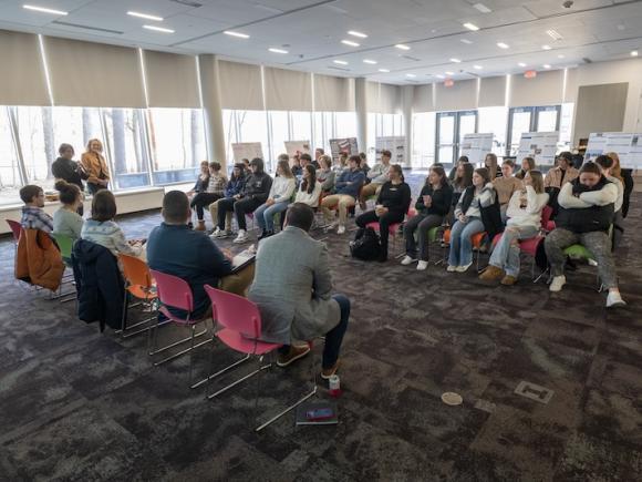 A crowd of students sitting on opposite sides of the room in rows, as part of Discover's Westfield's Shark Tank event.