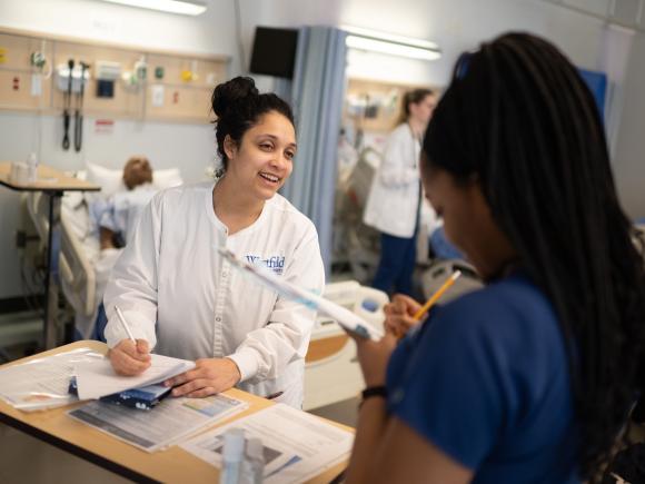 Two nursing students in a simulation lab practicing clinical skills.