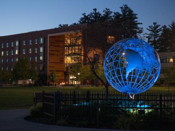 Campus globe at night with blue light shining on it.