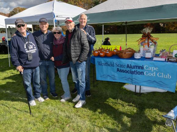 Alumni Stand in front of decorated homecoming tent