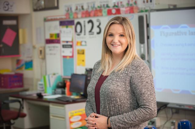 Elementary education teacher smiling in a classroom.