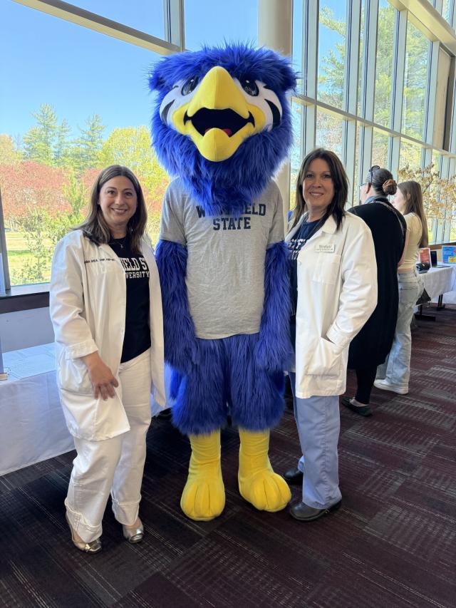 Two staff members from Health Services stand smiling with Nestor.