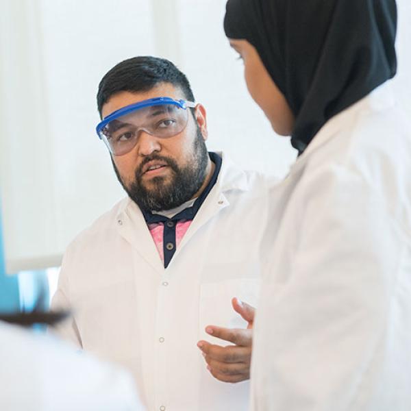 A professor talks with a student during a lab activity.