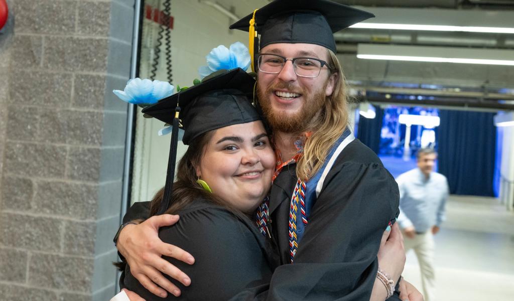 Two students smiling together at commencement ceremony.