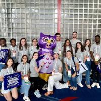 PA students at the American Academy of Physician Assistants (AAPA) National Conference in Houston, Texas. They are posing with a purple owl and hold blue signs that say 'Rally Towel'.