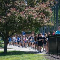 A photo of students lining up for New Orientation Day. They gather outside of the Dining Commons in rough rows of two.