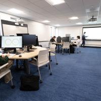 Students work at computer stations while an instructor leads a class in Westfield State University's newly renovated Center for Interdisciplinary Informatics, featuring collaborative workspaces and technology for hands-on learning.